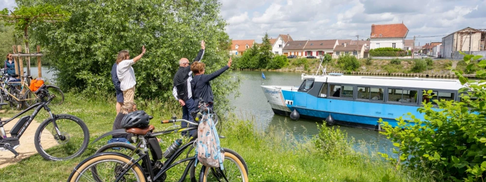groupe de cyclistes qui saluent une péniche
