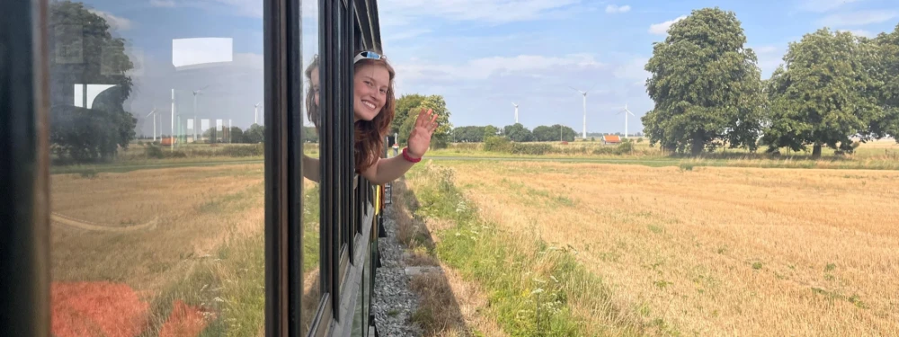 en vadrouille - jeune fille qui fait coucou depuis un train dans la campagne