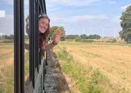 en vadrouille - jeune fille qui fait coucou depuis un train dans la campagne