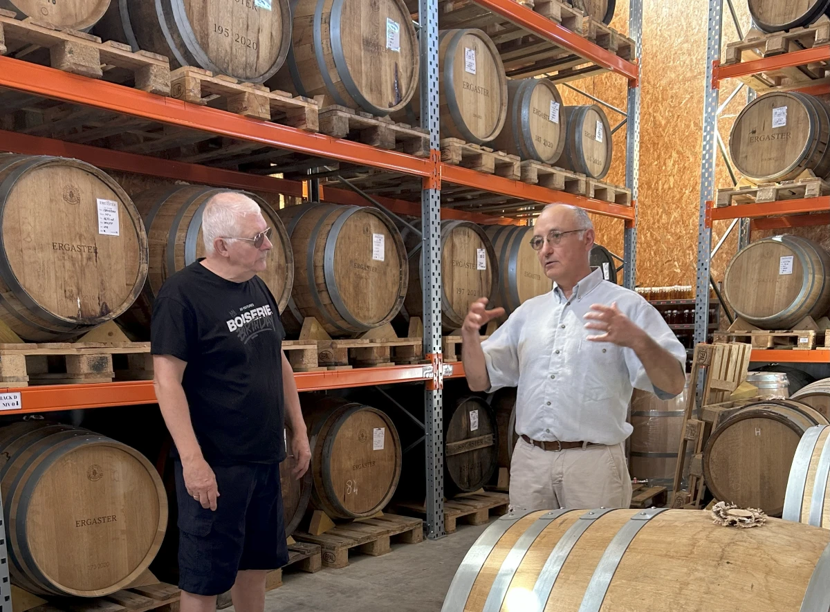 deux hommes devant des futs de whisky
